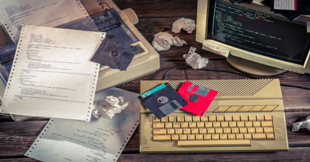 Dot Matrix printer with an old style computer and paper and floppy disks.