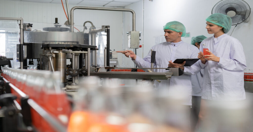 A quality supervisor and food and beverage technician discuss the process control of food before sending the product to the customer.